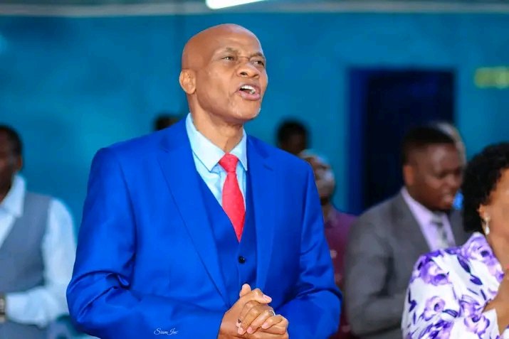 Bishop John Kaberere praying in a blue suit