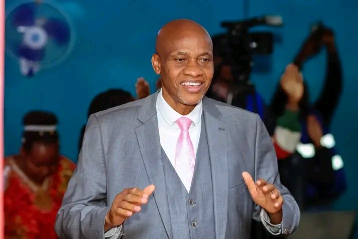 Bishop John Kaberere in a grey suit worshipping